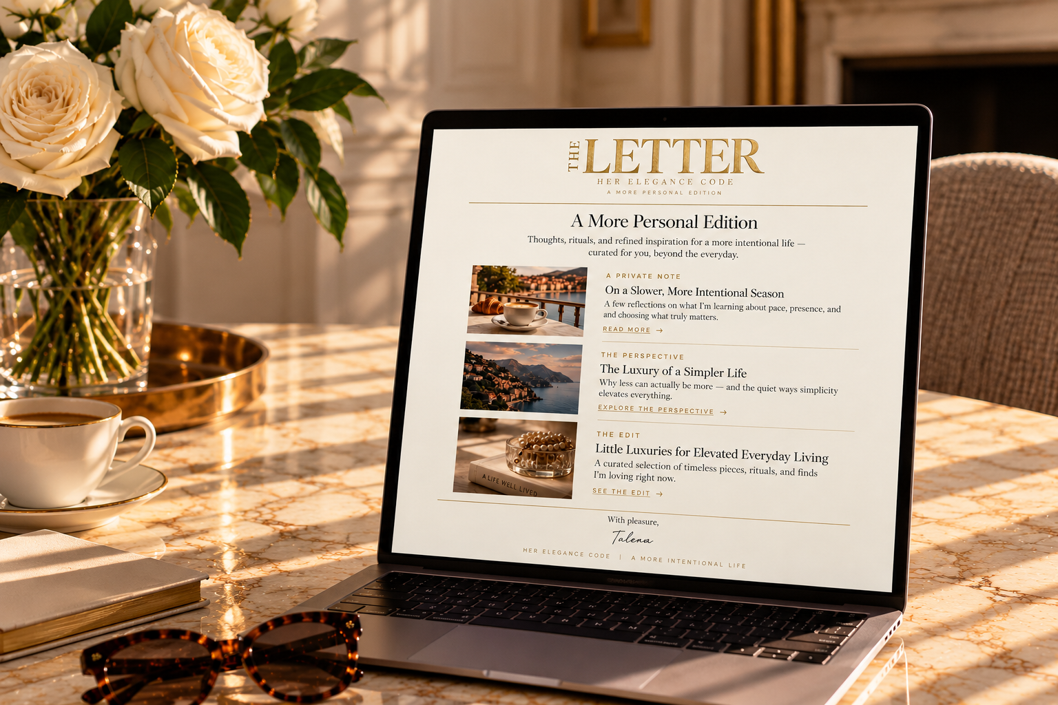 Laptop displaying The Journal Newsletter on a sunlit marble desk beside cream roses and tortoiseshell sunglasses.